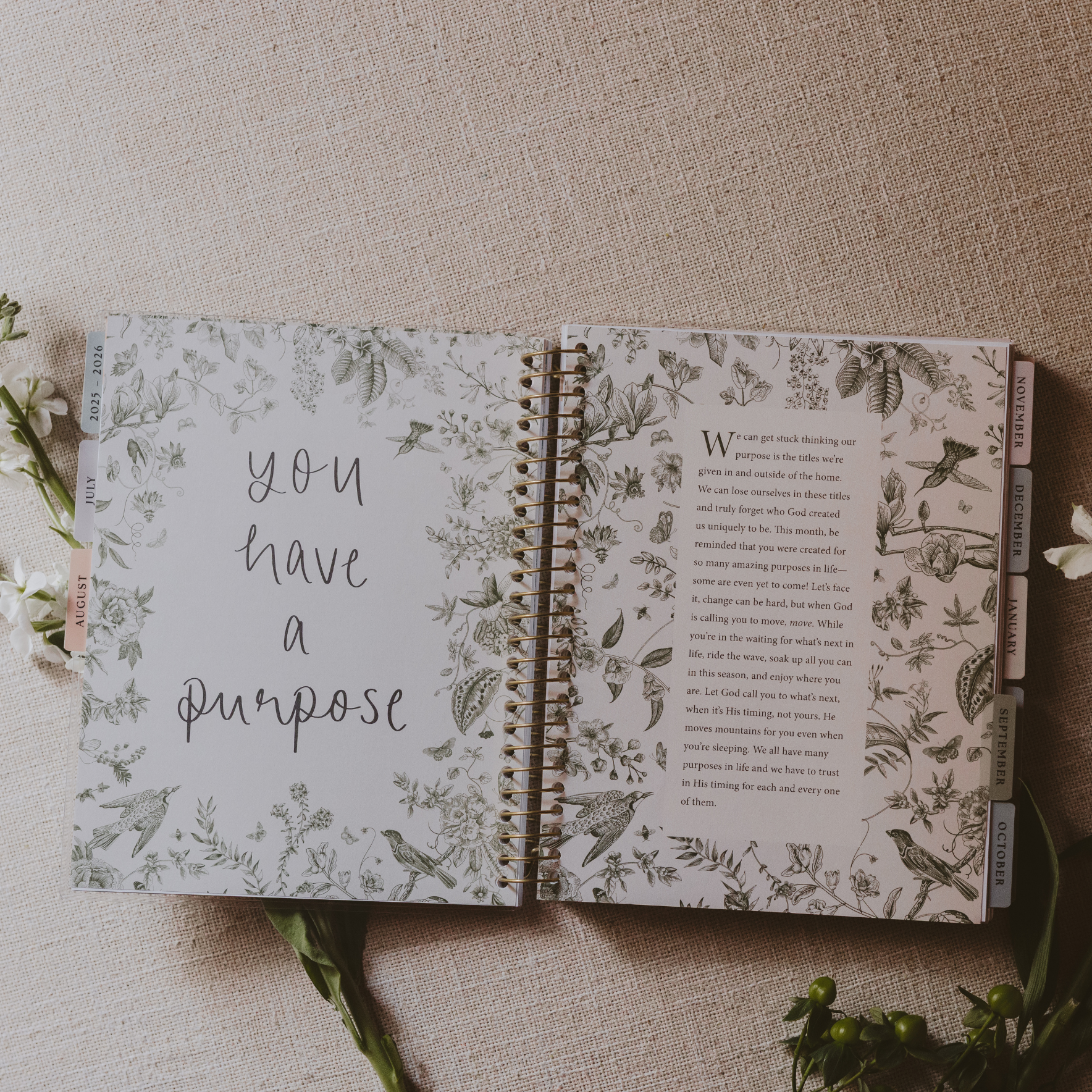 Open notebook with floral design and motivational text on a textured surface