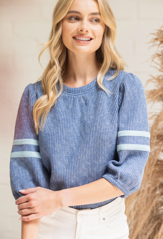 Woman wearing a blue sweater with white stripes on a neutral background