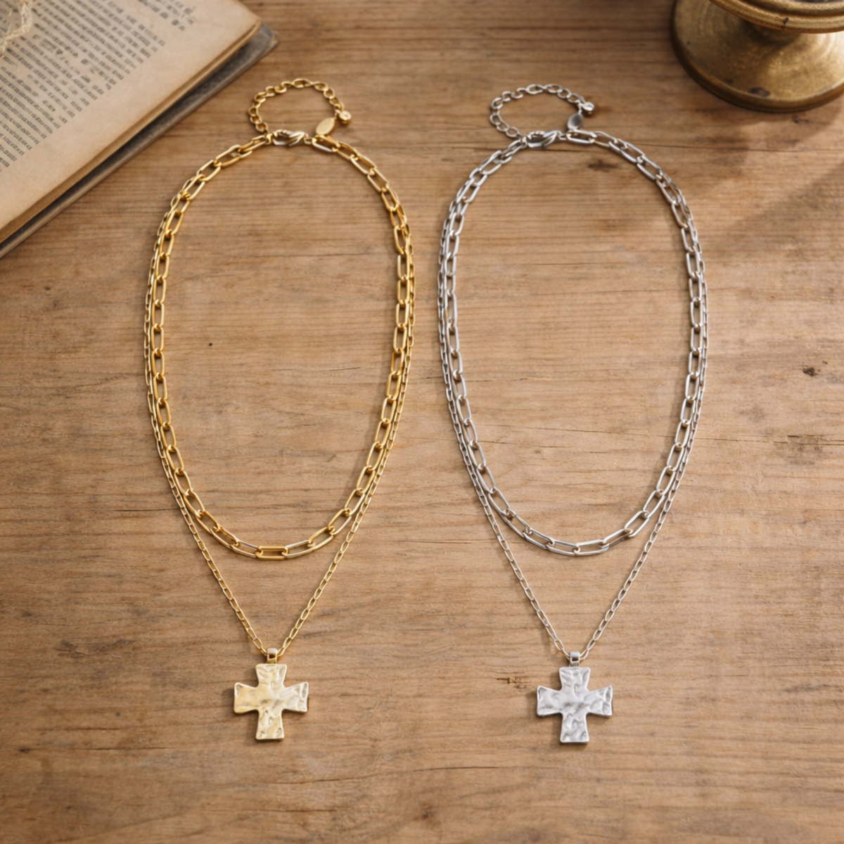 Two chain necklaces with cross pendants on a wooden surface.