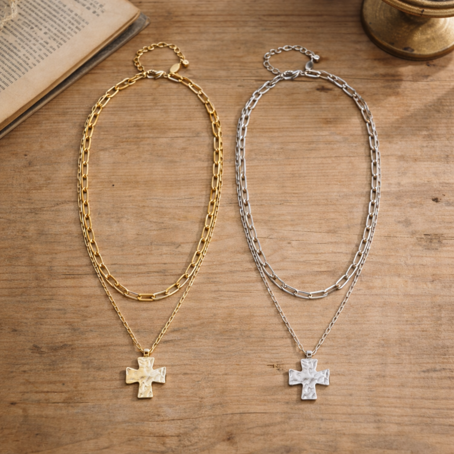 Two chain necklaces with cross pendants on a wooden surface.