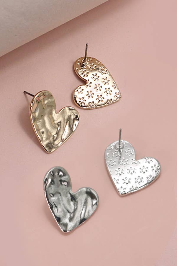 Heart-shaped earrings in gold, silver, and bronze on a pink background