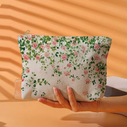 Floral-patterned pouch held by a hand against an orange background