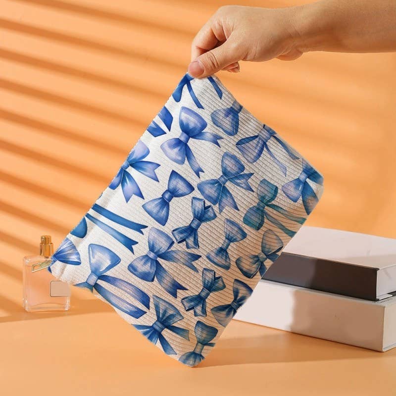 Hand holding a pouch with blue bow pattern against an orange background