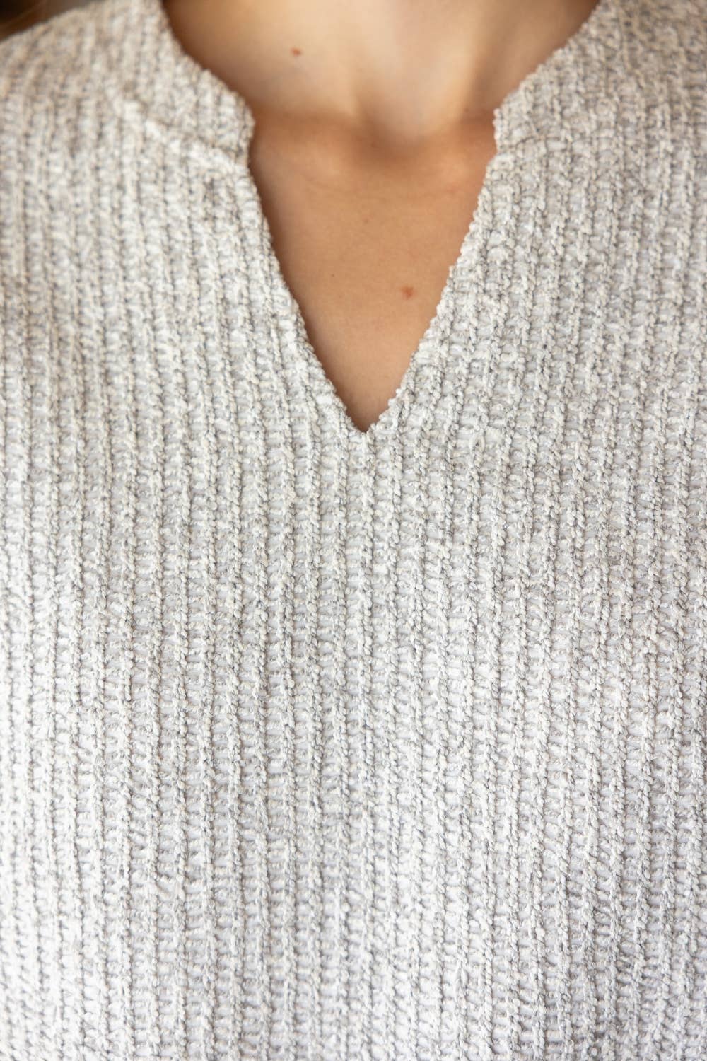 Close-up of a textured gray sweater with a V-neck