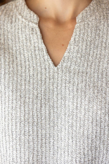 Close-up of a textured gray sweater with a V-neck