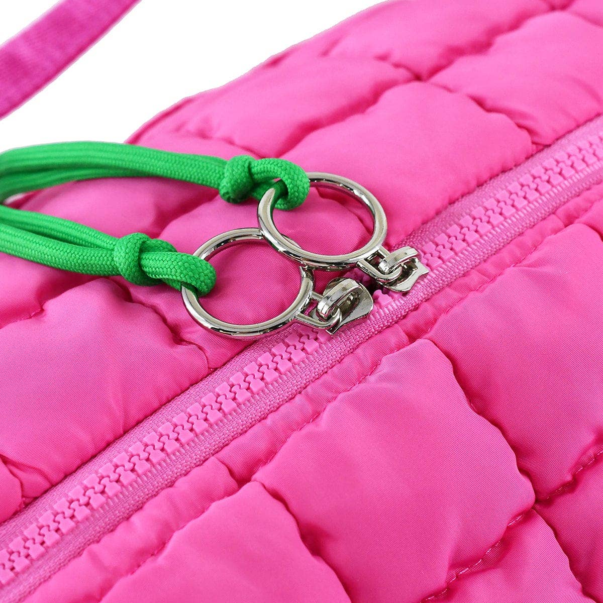 Close-up of a pink jacket with a green keychain attached to the zipper.