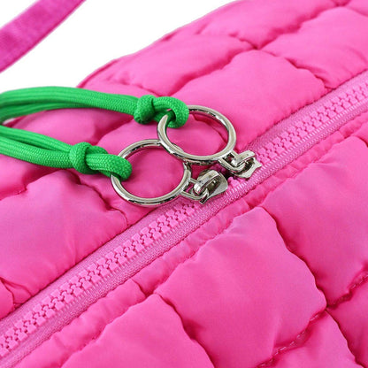 Close-up of a pink jacket with a green keychain attached to the zipper.