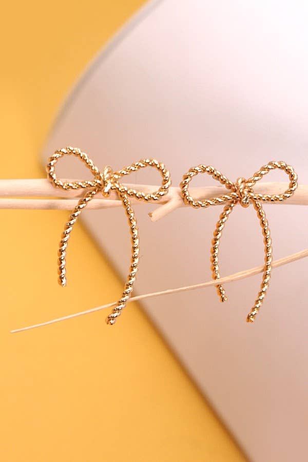 Gold bow-shaped earrings on a yellow and beige background