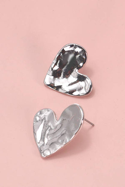 Heart-shaped silver earrings on a pink background