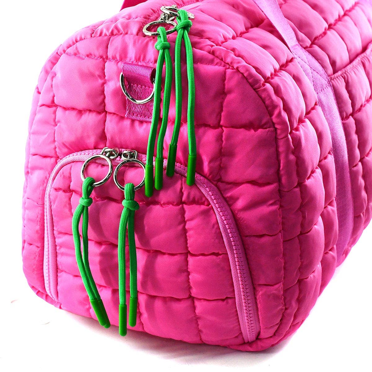 Pink quilted bag with green keychains on a white background