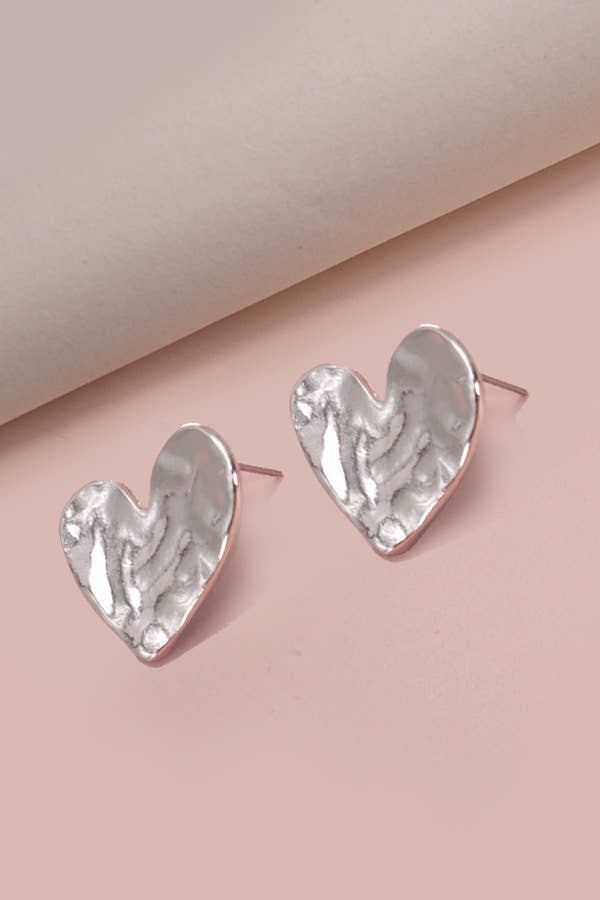 Heart-shaped silver earrings on a pink background