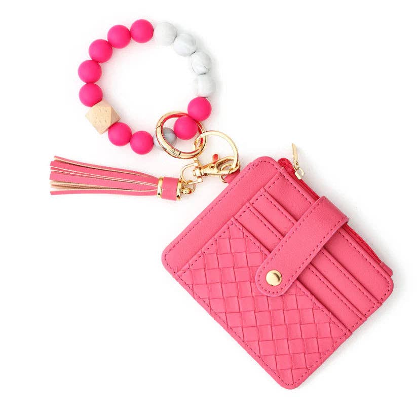Pink woven wallet with tassel keychain and pink beaded bracelet on a white background